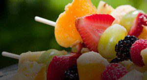 Close-up of colorful fruit skewers with strawberries, grapes, and melon.