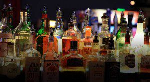 Assorted liquor bottles illuminated in a dim bar setting.