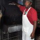 jerk master peter preparing his grill at trellis bay market