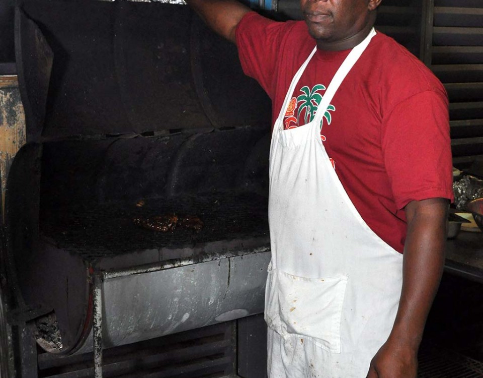 jerk master peter preparing his grill at trellis bay market