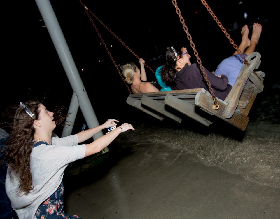 Three women pushing their friends at the swing