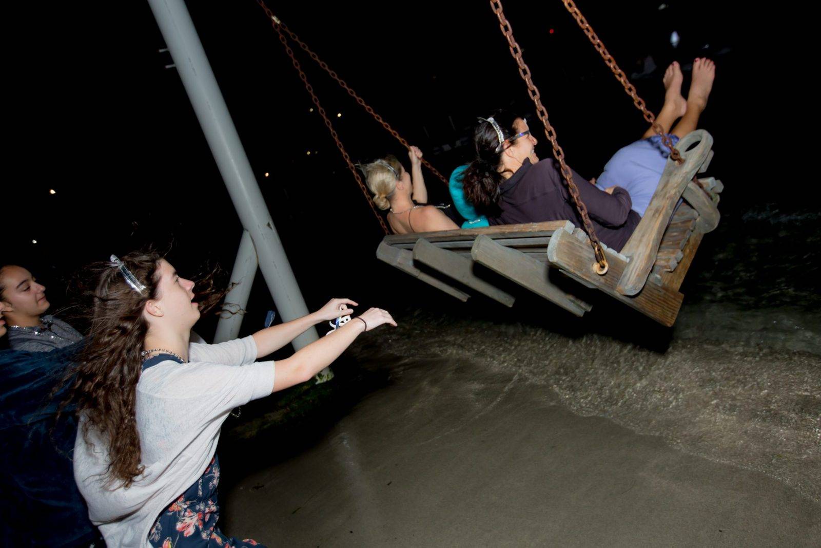 Three women pushing their friends at the swing