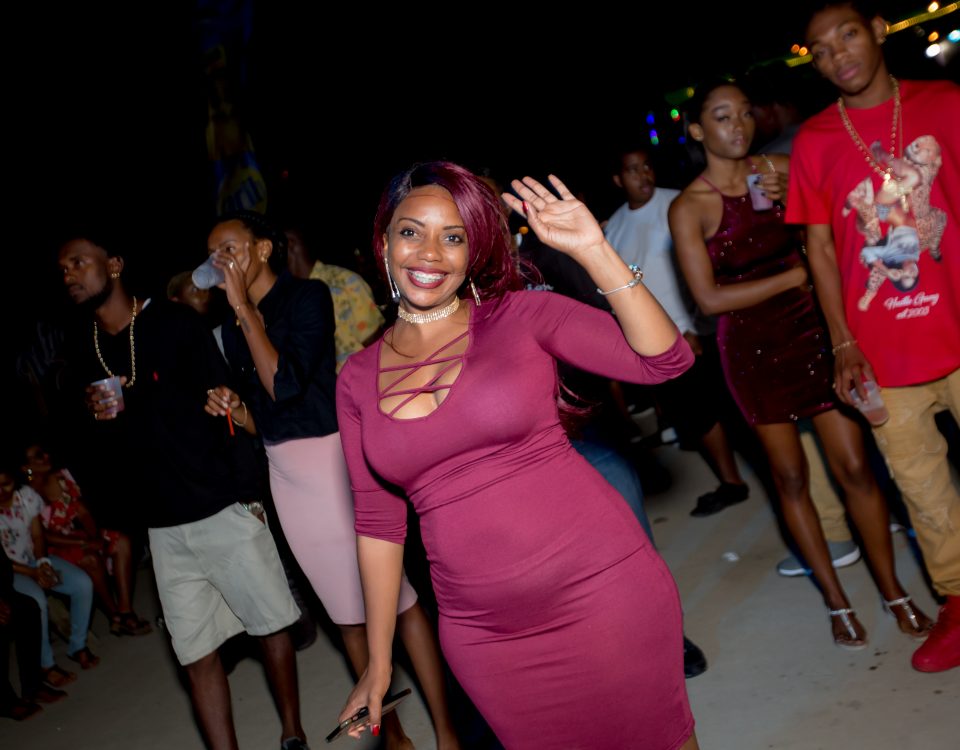 A woman in a maroon dress waving her hand