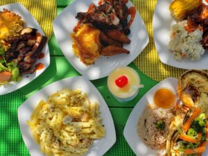 A colorful spread of grilled chicken, pasta, and desserts on a yellow checkered tablecloth.