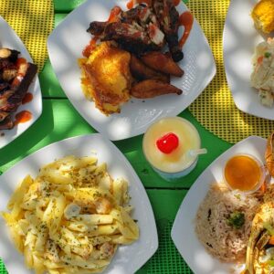 A colorful spread of grilled chicken, pasta, and desserts on a yellow checkered tablecloth.