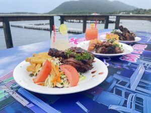 Plates of food and drinks by water.