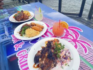 Grilled meats and drinks on colorful table.