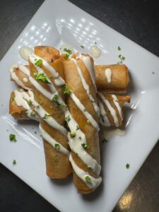 Crispy rolled tacos with creamy sauce drizzle.